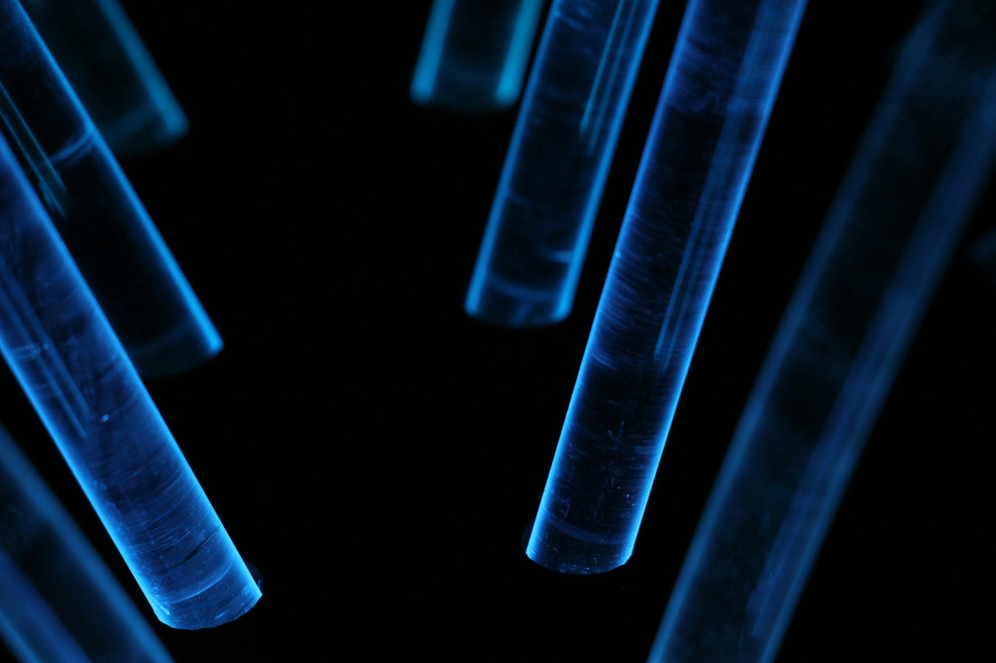 Glowing blue laboratory test tubes on black background representing biohacking science and longevity supplement research UK