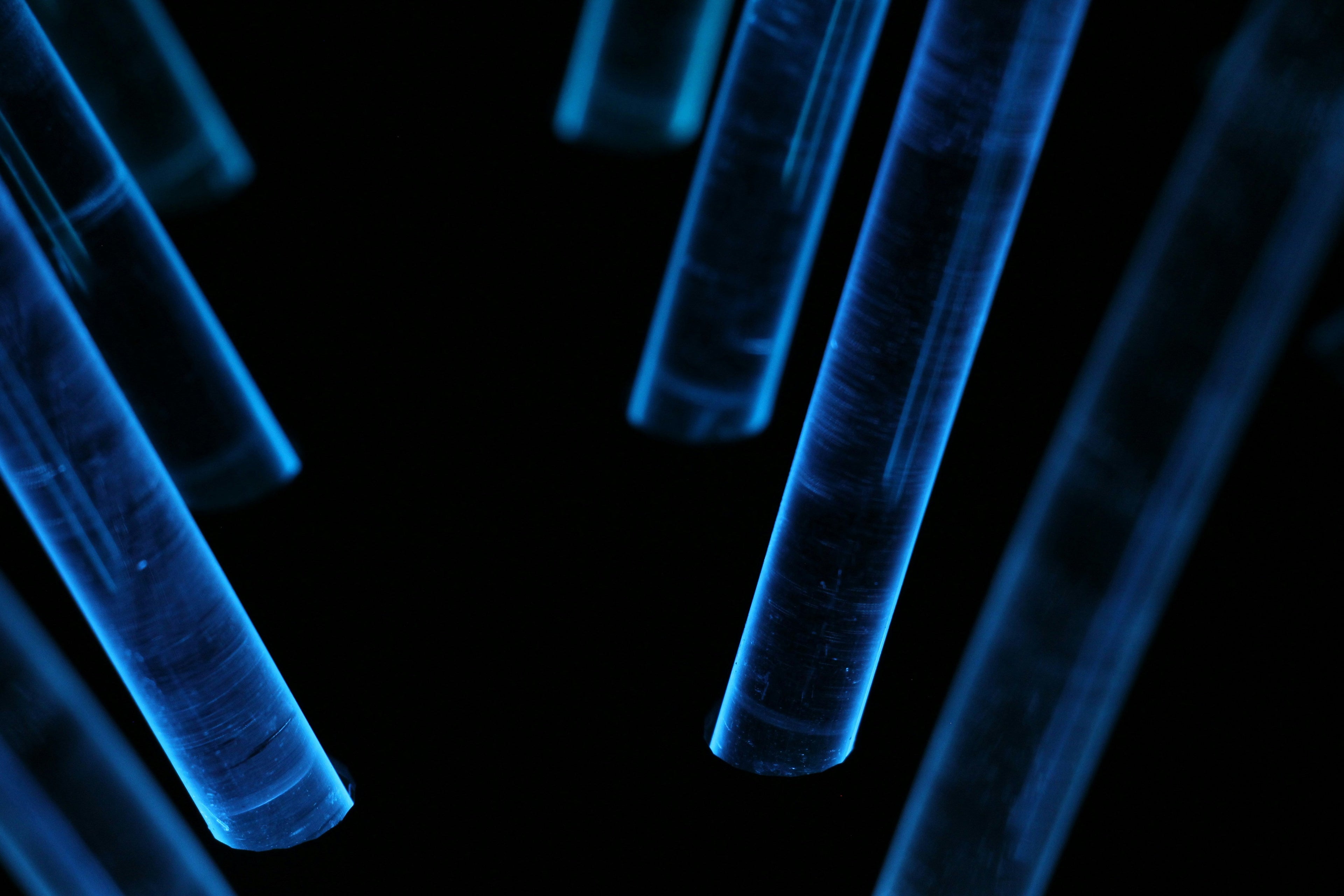 Glowing blue laboratory test tubes on black background representing biohacking science and longevity supplement research UK